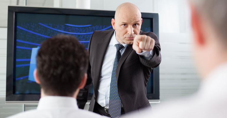 boss pointing at an employee angrily during a meeting