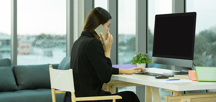 young Asian businesswoman in black suit is calling smartphone and sitting in a modern office
