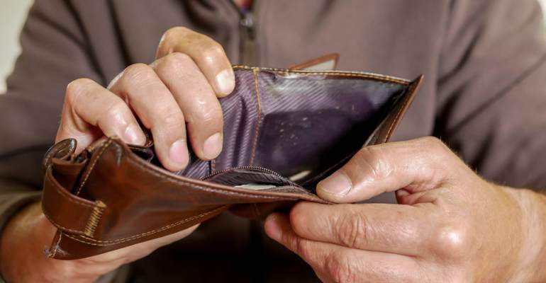 Person looking inside an empty wallet after being paid under minimum wage