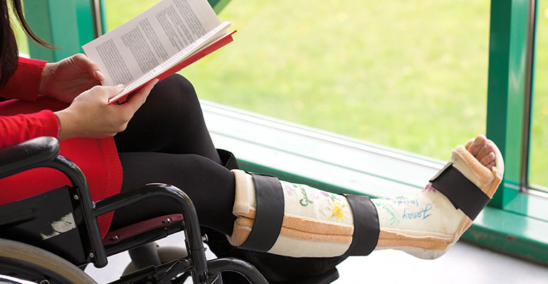 Girl in a wheelchair with one leg in a cast