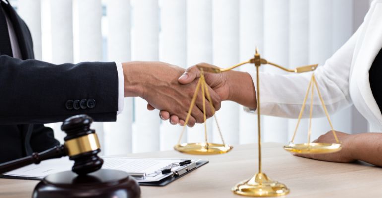 Two lawyers shaking hands after negotiating a settlement