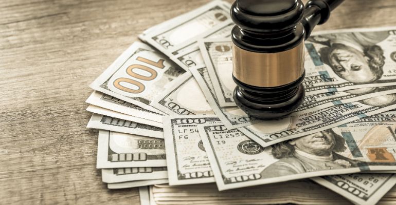 Gavel resting on top of money from a legal settlement