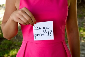Woman holding a note saying "can you prove it?"