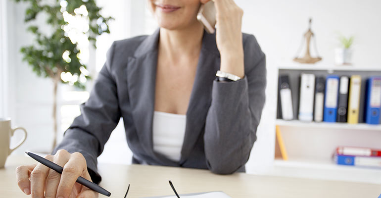 woman sitting at her desk while talking on the phone