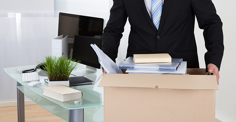 man holding box of belonging at his desk