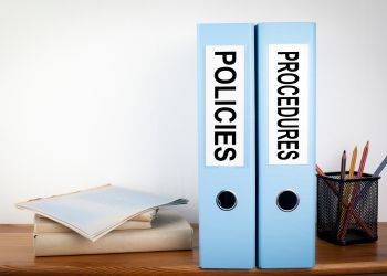 Blue binders containing workplace unpaid overtime policies and procedures