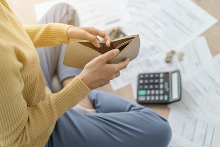 Person opening an empty wallet after their employer reduced their pay
