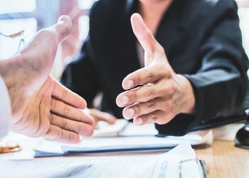 Two people shaking hands and agreeing on a settlement