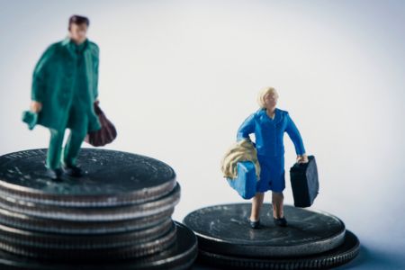 gender pay gap represented by figures on coin stacks