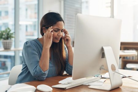 office worker showing stress while reviewing information on screen