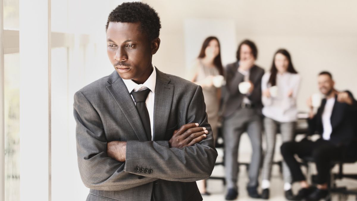 Employee standing apart while coworkers laugh in an office