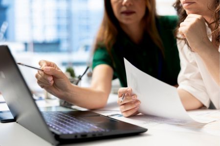 employees reviewing a background check report on a laptop.