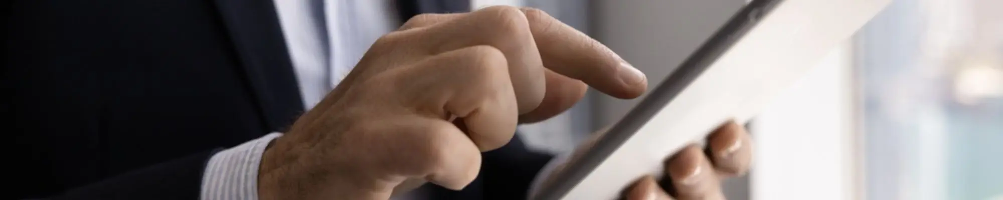 Business professional using a tablet while standing near an office window