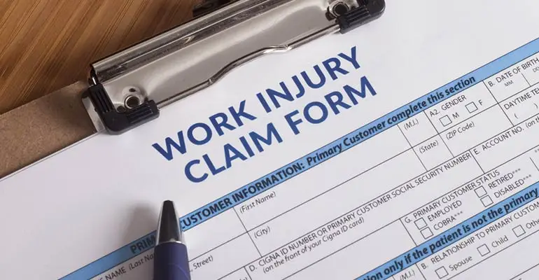Work injury form on clip board with pen