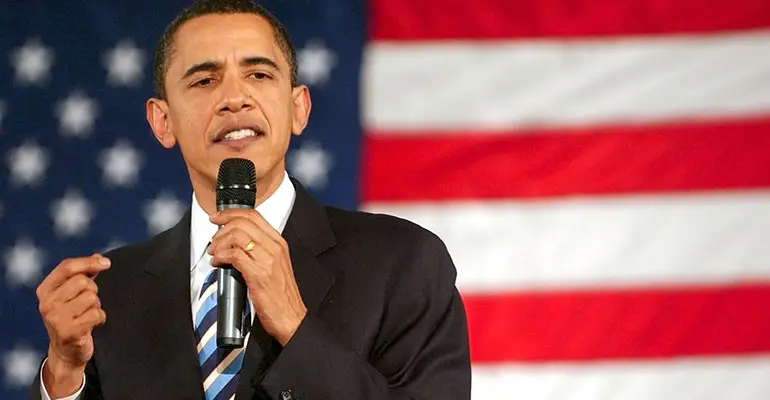 President Obama speaking with microphone in hand with American flag in background