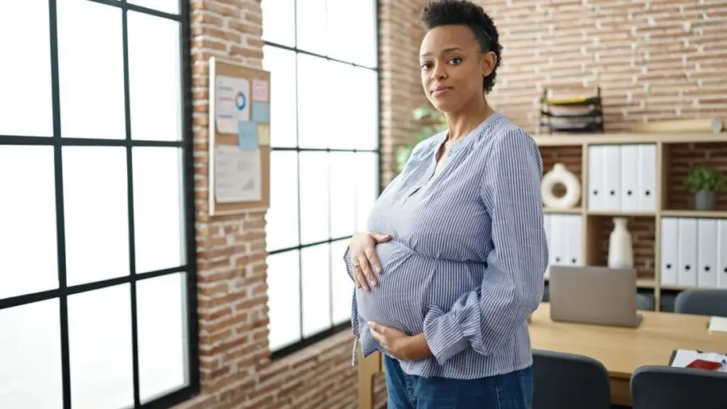 pregnant employee standing in an office workplace during the workday