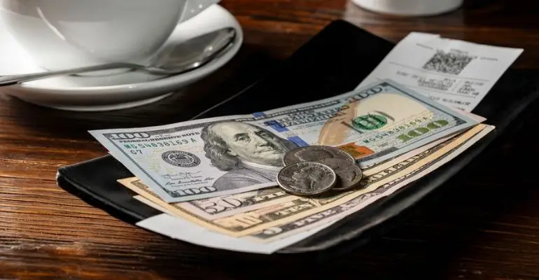 cash tip on restaurant bill with receipt and US dollars