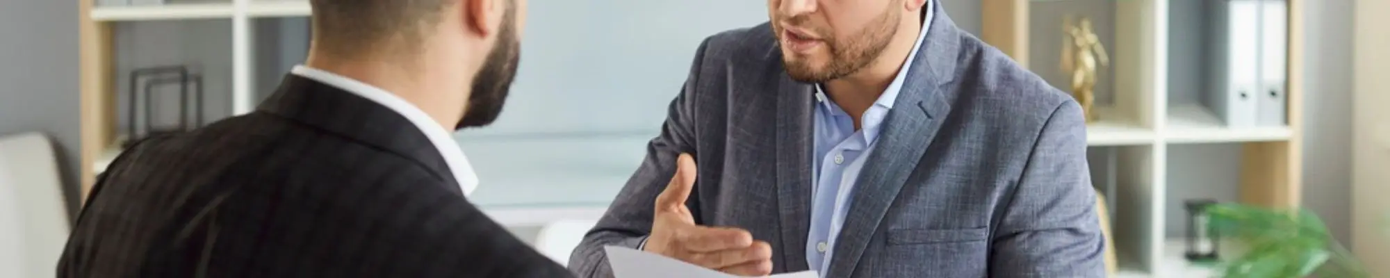 Two male professionals discussing a contract during an office meeting