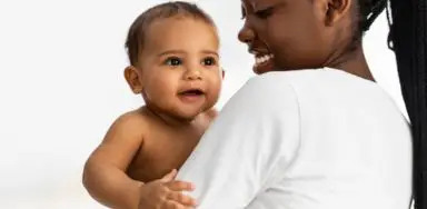 A woman holding a baby over her shoulder