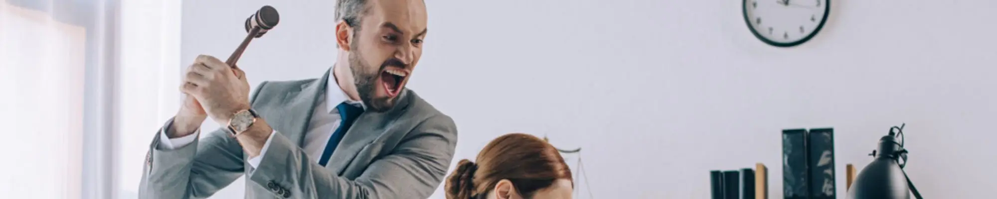 Angry businessman holding a gavel behind a female employee reviewing a contract