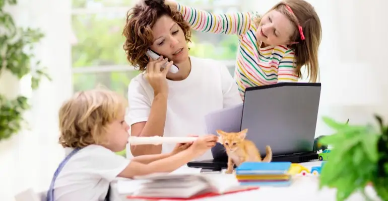 Mother dealing with two kids and a kitten while working