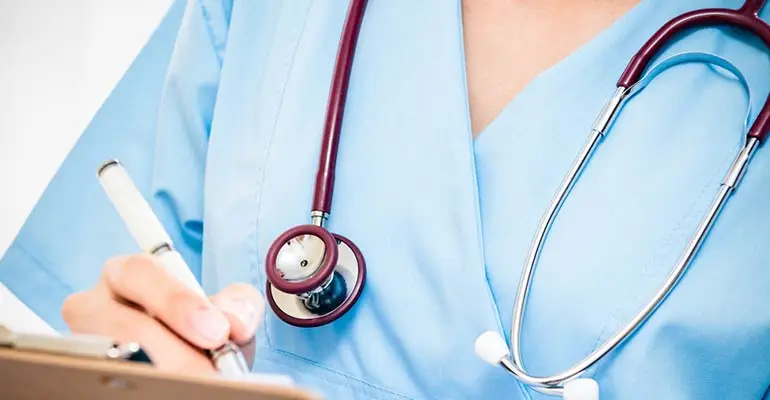 Nurse filling out a form on clipboard and wearing stethoscope