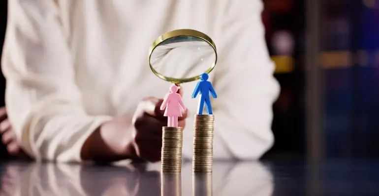 gender pay comparison magnifying glass over stacked coins