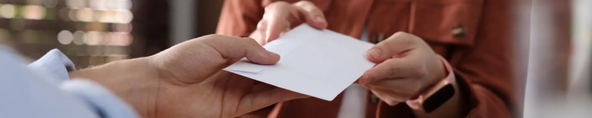 Female employee receiving a compensation envelope across an office desk