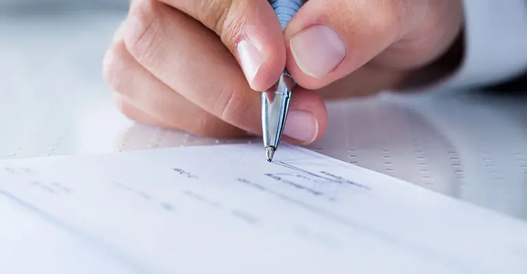 man signing check with pen